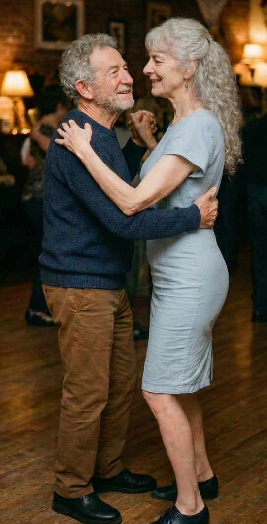 Older couple dancing together at a warmly lit community gathering